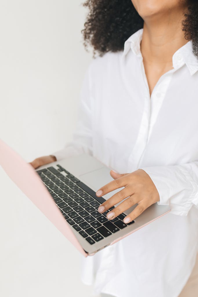 Close-up of woman holding laptop against a soft white background.